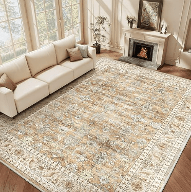 Un salon lumineux avec un canapé beige, un tapis décoratif aux motifs floraux, et une cheminée en pierre.